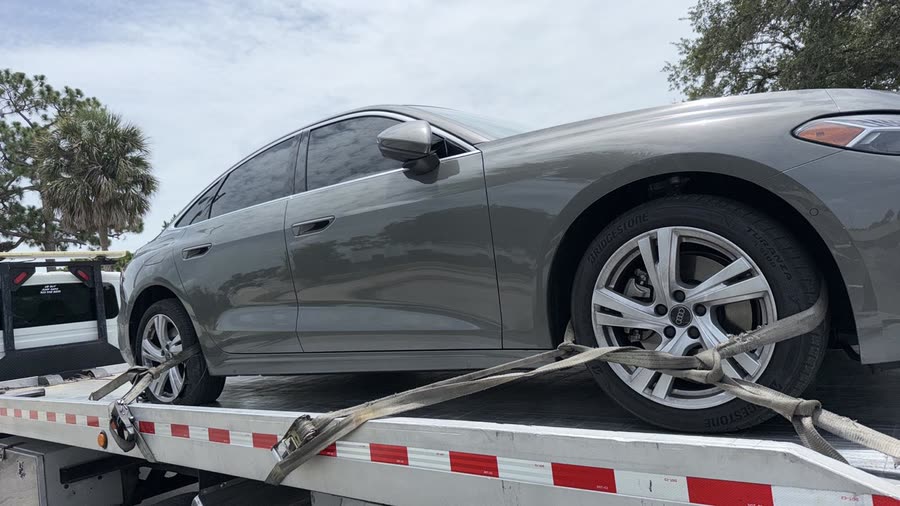 Luxury sedan secured with soft straps on the flatbed