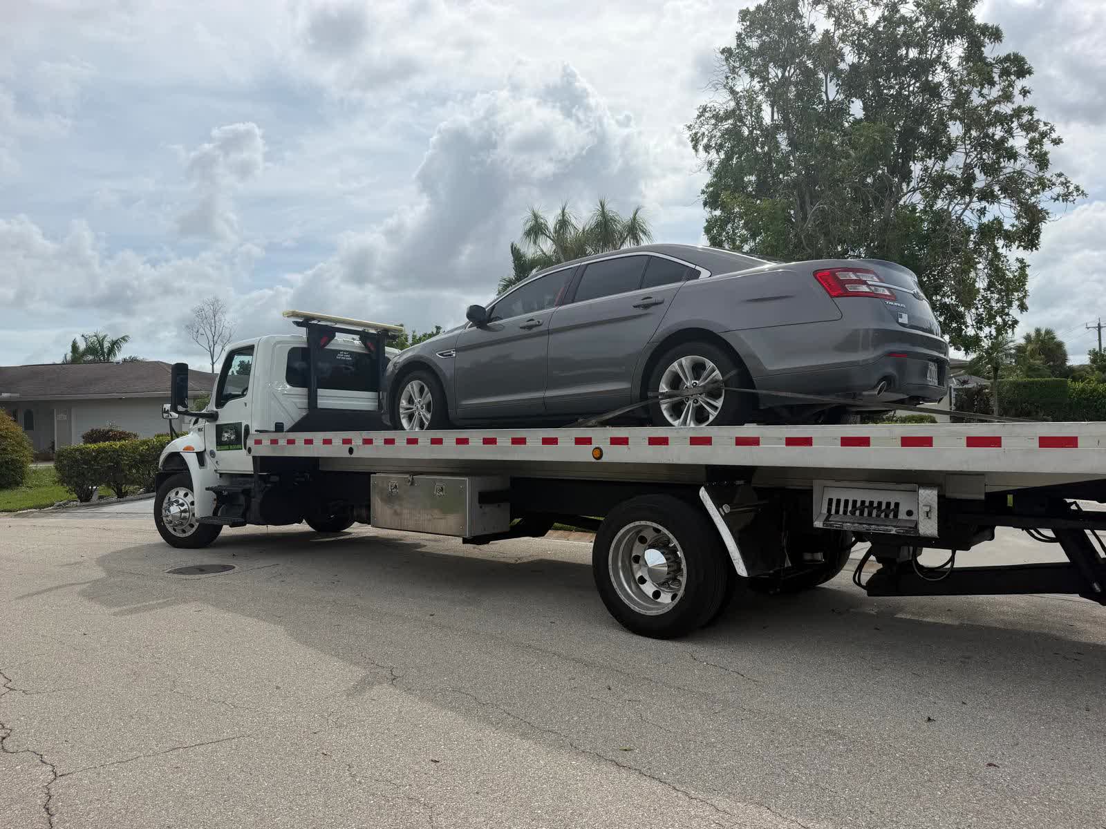 Brayan Towing truck with a loaded sedan on a Cape Coral street